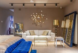Modern Airbnb living room with white sofa, blue ottoman, gold mirror, and stylish lamps, reflecting professional cleaning standards for hosts in Nashville